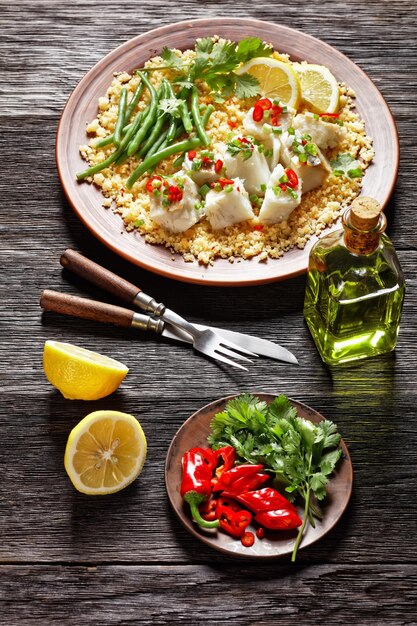 Bacalhau com todos bacalhau com feijão verde cozido no vapor bulgur polvilhado com pimenta malagueta e cebolinha em um prato rústico em uma mesa de madeira cozinha portuguesa vista vertical