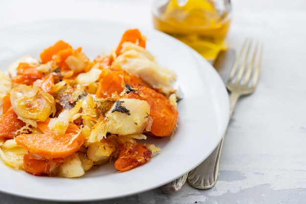 Bacalhau frito com batata-doce em prato branco sobre fundo de cerâmica