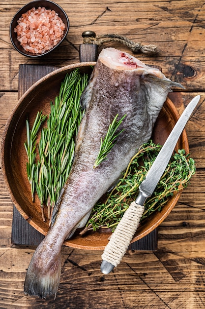 Bacalhau ou bacalhau cru em prato de madeira com ervas