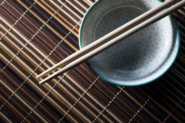 Bacia cerâmica com os chopsticks no fundo de bambu