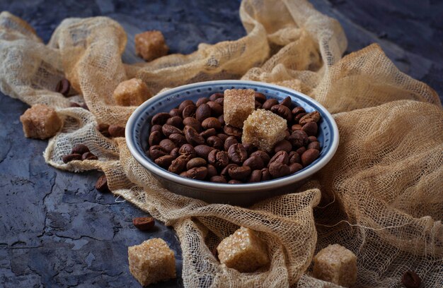 Bacia de feijões de café e de açúcar de bastão marrom. Foco seletivo