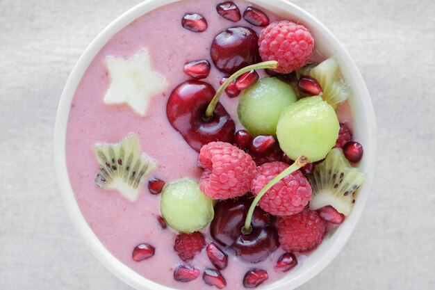 Bacia de smoothie rosa e verde vermelho com cereja, melão, morango, framboesas e romã