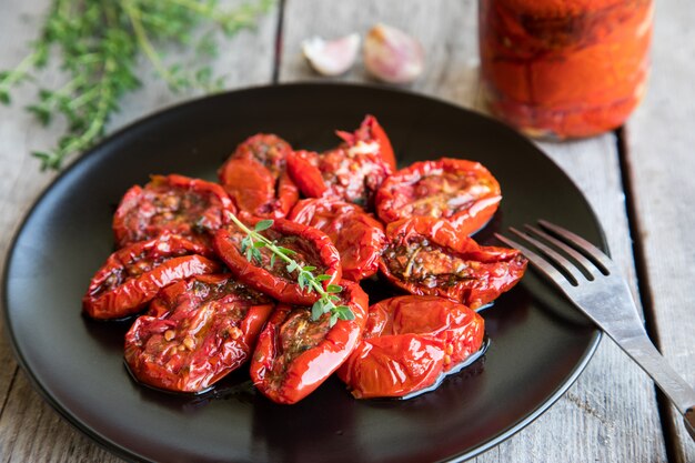 Bacia de tomates secados sol no fundo de madeira. Tomate seco ao sol com azeite e ervas