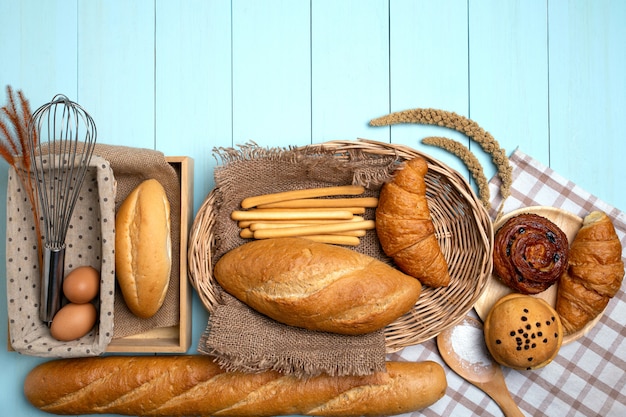 Backbrot auf blauem Holztisch. Verschiedene Brot- und Garbenweizenohren.