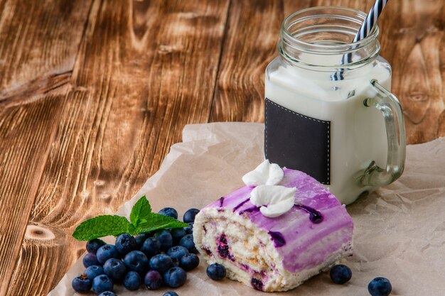 Backen Sie mit Blaubeeren und Milchshake auf einem Holztisch zusammen