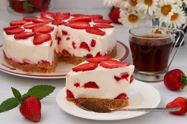 Backen Sie mit Erdbeeren zusammen, ohne das Backen, das auf einer Platte auf einem Weiß gelegen ist