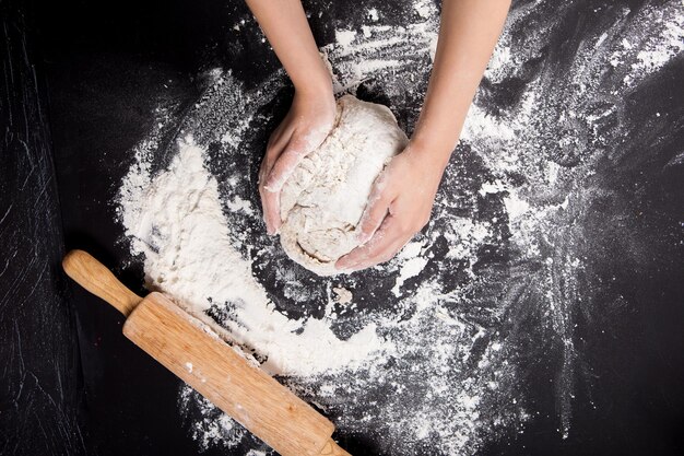 Backen vorbereiten Hintergrund Weibliche Hände kneten Teig auf der Arbeitsplatte