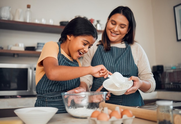 Backende Familie und Kinder mit Mutter und Tochter, die in der Küche ihres Hauses über das Kochen lernen. Essen Sie Kinder und helfen Sie mit einem Mädchen und einer Frau, die ihrem Kind beibringt, wie man mit Eiern oder Mehl backt