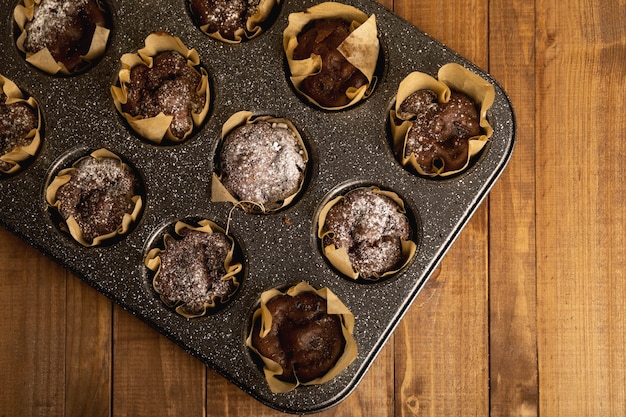 Backform mit leckeren Schokoladenmuffins auf dem Holztisch