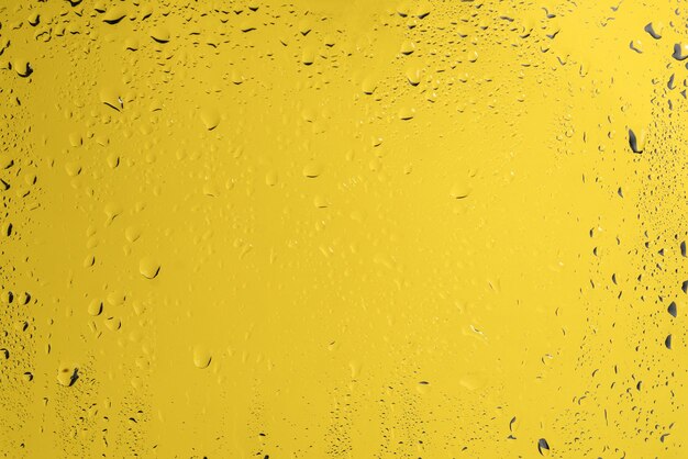 Backgrond amarillo con gotas de agua. Copie el espacio.