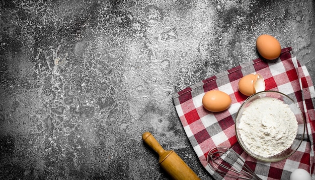 Backhintergrund Mehl und frische Eier zum Backen auf rustikalem Hintergrund