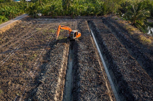 Backhoe vista de alto ângulo é dingging o jardim do sulco e área agrícola Tailândia