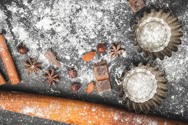 Backkonzept Cupcake-Form und Lebensmittelzutaten auf dunklem Hintergrund bereiten sich auf das Kochen von Draufsicht vor