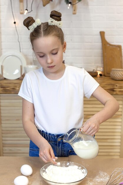 Backkonzept Porträt eines lächelnden süßen kleinen Mädchens, das Ingwerkekse mit Keksen kocht Ein positives Kind in der Küche bereitet hausgemachte Kuchen für das Rezept der Omas zum Muttertag zu