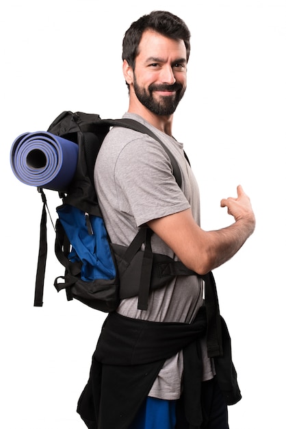 Backpacker guapo apuntando hacia atrás sobre fondo blanco