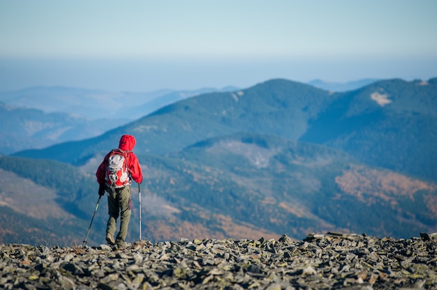 Backpaker masculino que camina en la cima rocosa de la montaña