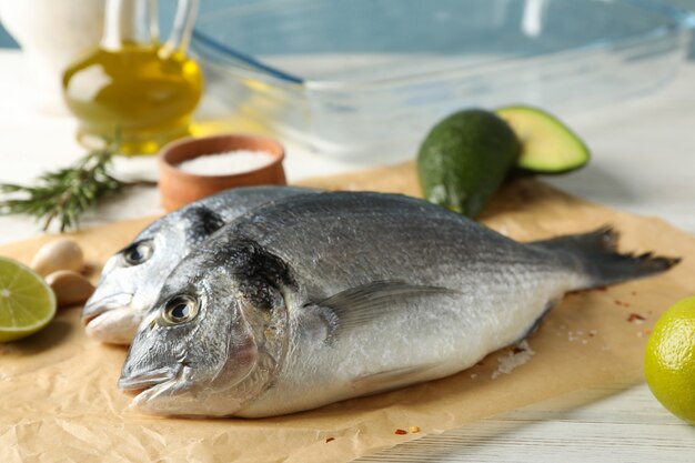 Backpapier mit Dorado-Fischen und Kochzutaten auf Holz