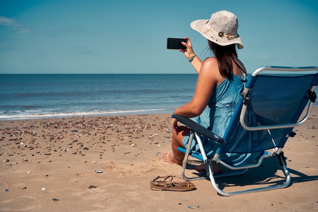 Foto backshot de una mujer joven sentada en la cama y tomar la foto de la se