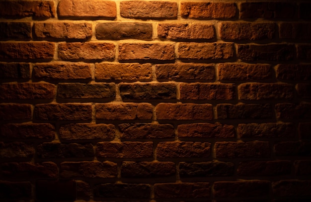 Backsteinmauer beleuchtet durch warmes Licht von einer Lampe