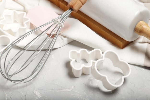 Backutensilien. Nudelholz, Keksform, Schneebesen auf grauem Hintergrund. Ostern-Konzept.