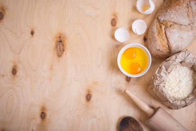 Backzutaten auf rustikalem Hintergrund mit Brot, Eierschale, Brot, Mehl, Nudelholz