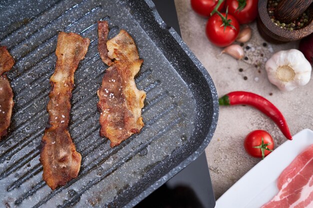 Bacon sendo cozido em frigideira grelha frigideira na cozinha doméstica