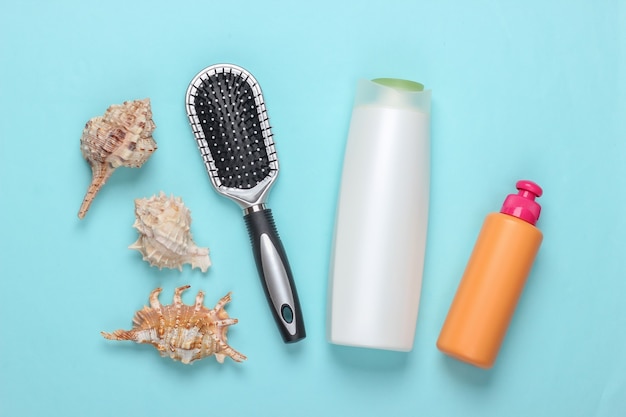 Bad Schönheitsprodukte. Flasche Shampoo, Herzmuscheln, Handtuch, Haarbürste auf Blau. Haarpflege