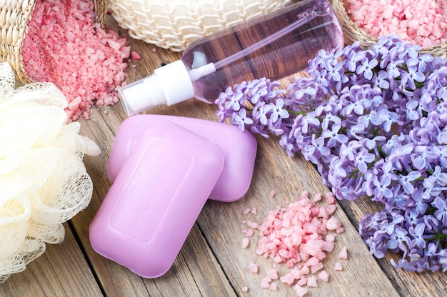 Badekurorthintergrund mit blühenden lila blumen und flasche aromaöl oder blumenhydrolat, kosmetische seife