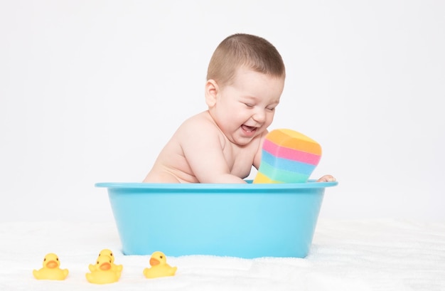 Baden des Babys in der Badewanne mit gelben Gummienten Baby sitzt in der Badewanne und schaut in die Kamera Viele Luftblasen fliegen im Badezimmer Junge nimmt Bad