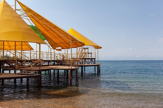 Badestelle oder Steg am Meer. Ein großer Pier mit einem Dach aus Holzplanken und rostigen Treppen, die absteigen