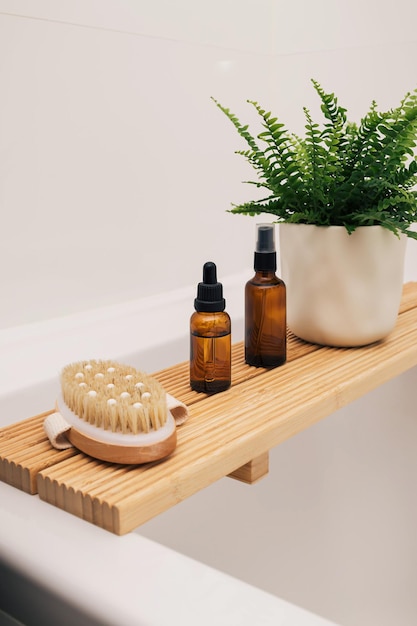 Badewanne aus Holz Tablett mit Beauty-Kosmetik-Öl-Flasche und Accessoires in einem modernen Interieur skandinavischen Badezimmer mit weißen Fliesen als Hintergrund Wohnkultur mit hölzernen Badewanne Tablett grüne PflanzenxD