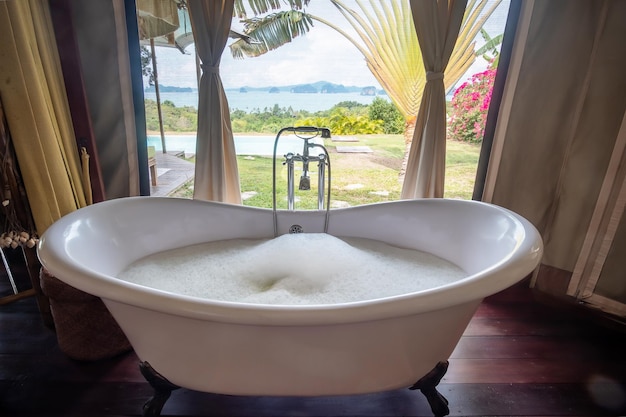 Badewanne mit Schaumblasen im tropischen Luxusresort vor wunderschönem Meereshintergrund Spa- und Entspannungskonzepte