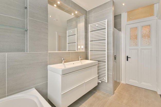 Badezimmer in grauem Design mit Keramikbadewanne und Waschbecken und Dusche