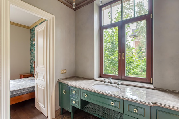 Badezimmer mit Marmorboden, luxuriöser goldener Kronleuchter, großes Fenster, grüner Waschtisch