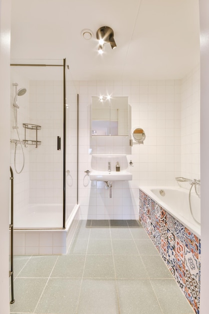 Badezimmerausstattung mit Fliesenmosaik-Badewanne, Waschbecken und Dusche in einer modernen Wohnung