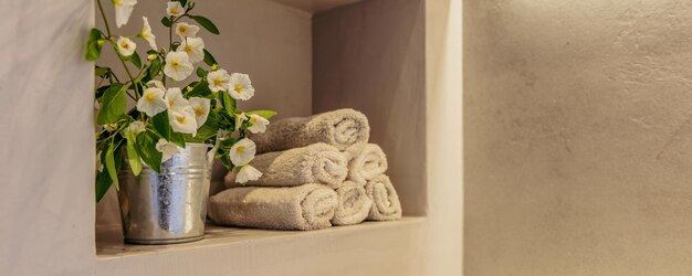 Badezimmerhandtücher gefaltet und blühende Pflanze modernes Design Spa Innenraum Detail Banner