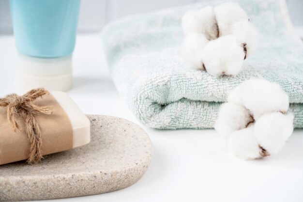 Badezimmertisch mit neuem Seifenstück auf Tablett und frischem, sauberem Handtuch, verziert mit flauschigen Wattebällchen