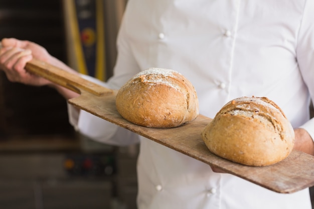 Bäcker, der Behälter des frischen Brotes zeigt