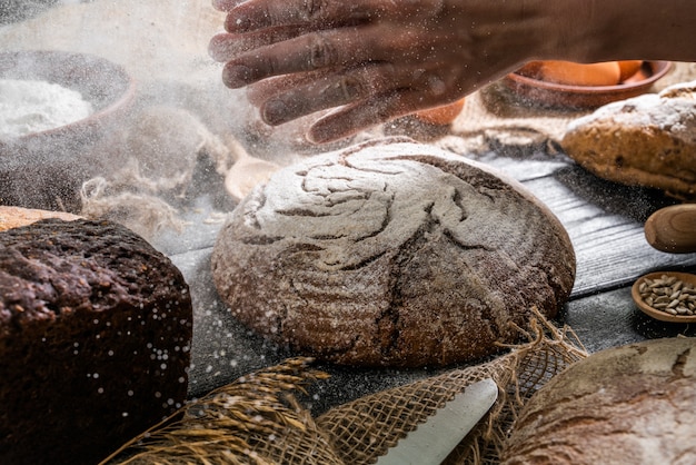 Bäcker, der Brot kocht. Frau schlägt Mehl über den Teig.