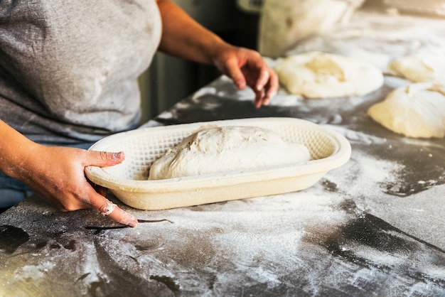 Bäcker, der Brot zubereitet. Nahaufnahme von Händen, die Teig kneten. Bäckerei-Konzept.