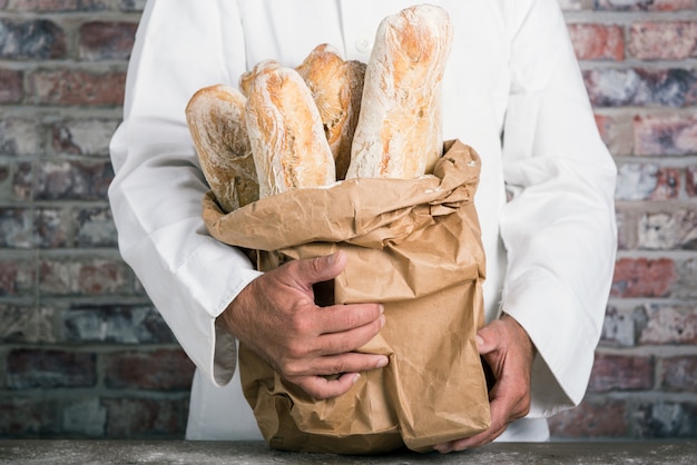 Bäcker, der französische Stangenbrote des traditionellen Brotes hält