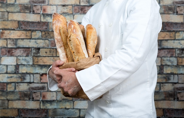 Bäcker, der französische Stangenbrote des traditionellen Brotes hält