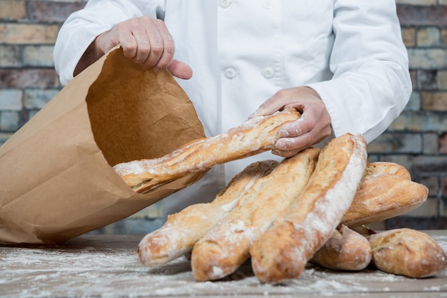 Bäcker, der französische Stangenbrote des traditionellen Brotes hält