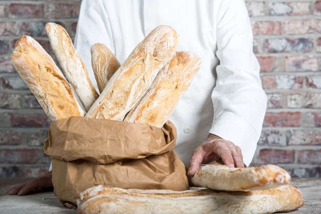 Bäcker, der traditionelle französische Stangenbrote hält