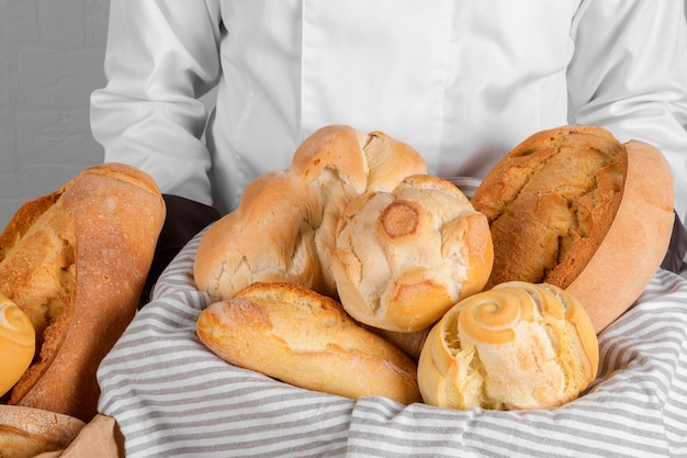 Bäcker hält ein frisches italienisches Weizenbrot im Korb auf weißem Wandhintergrund