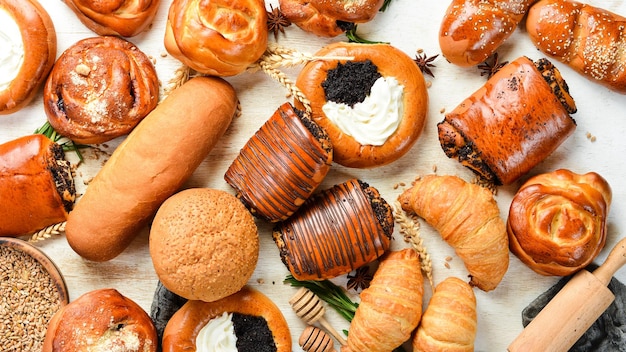 Bäckerei Satz Brötchen mit Marmelade, Quark, Mohn und Sesam auf weißem Holzhintergrund Backen aus Roggen und Mehl Draufsicht Rustikaler Stil