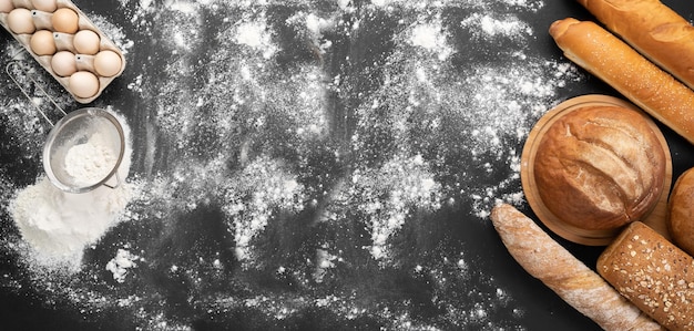 Foto bäckereierzeugnisse goldene rustikale brotskorben und brötchen auf einem schwarzen brett hintergrund eier siebe und mehl stillleben von oben gefangen banner