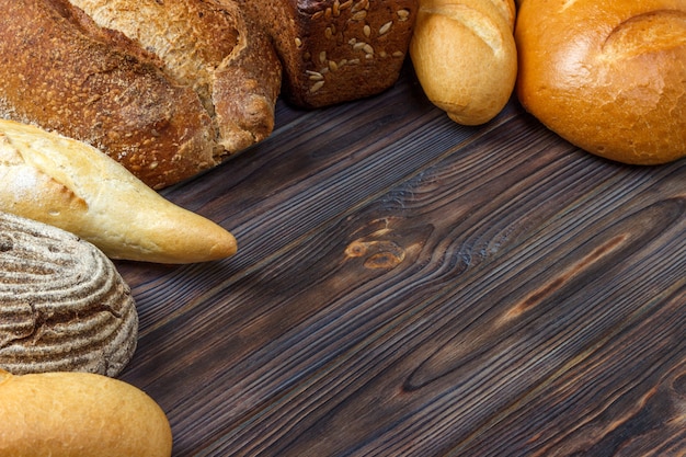 Bäckereihintergrund, Brotzusammenstellung auf schwarzem hölzernem Hintergrund