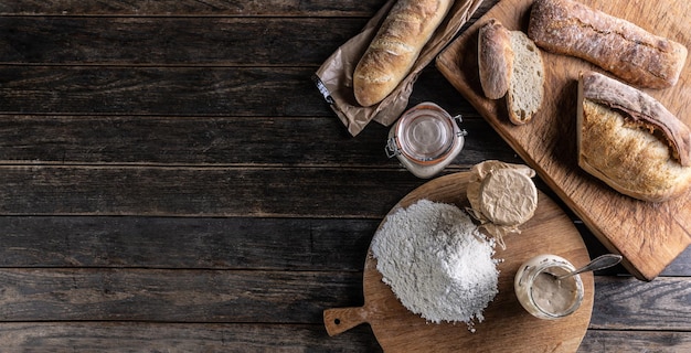 Bäckereikonzept Mehlbrot und Gläser mit Roggensauerteig auf dem Tisch Draufsicht