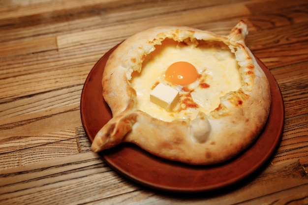 Bäckerhände, die Khachapuri auf Küchentisch vorbereiten. Kochen Sie traditionelle georgische Leckerei mit rohem Teig und Ei.